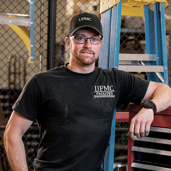 Man in classes and t-shirt leans on a tool chest.