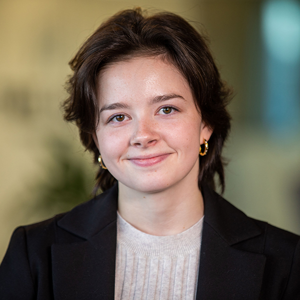 Young woman in black blazer smiles.