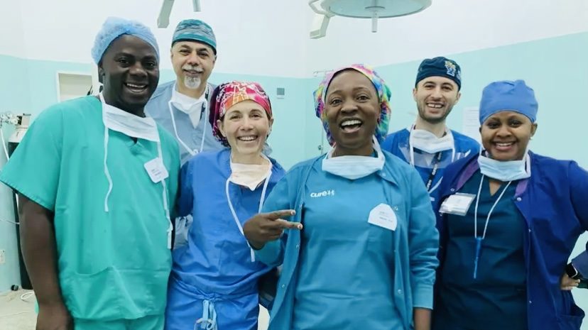 Woman stands with group of smiling medical professionals.