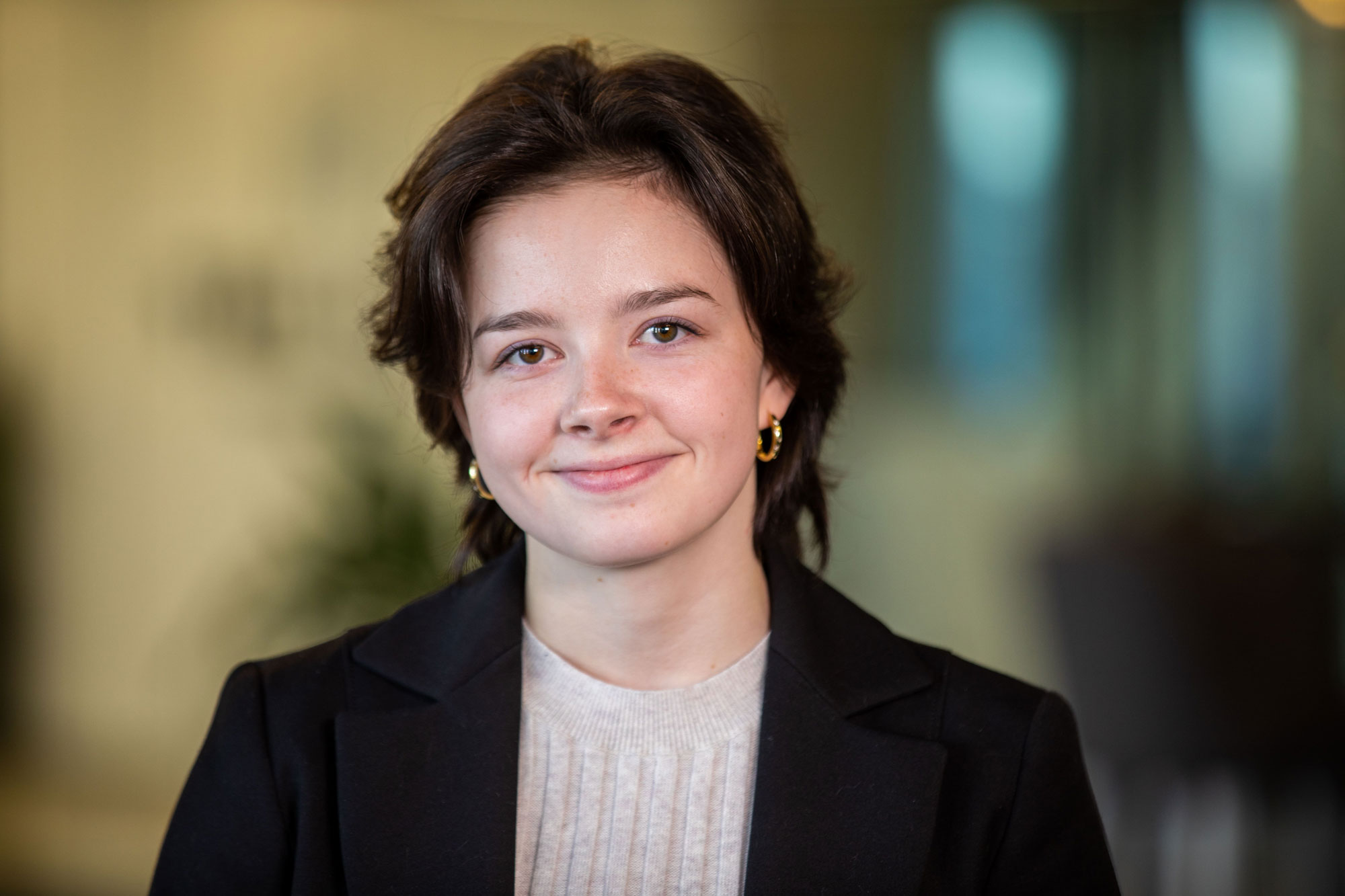 Young woman in black blazer smiles.