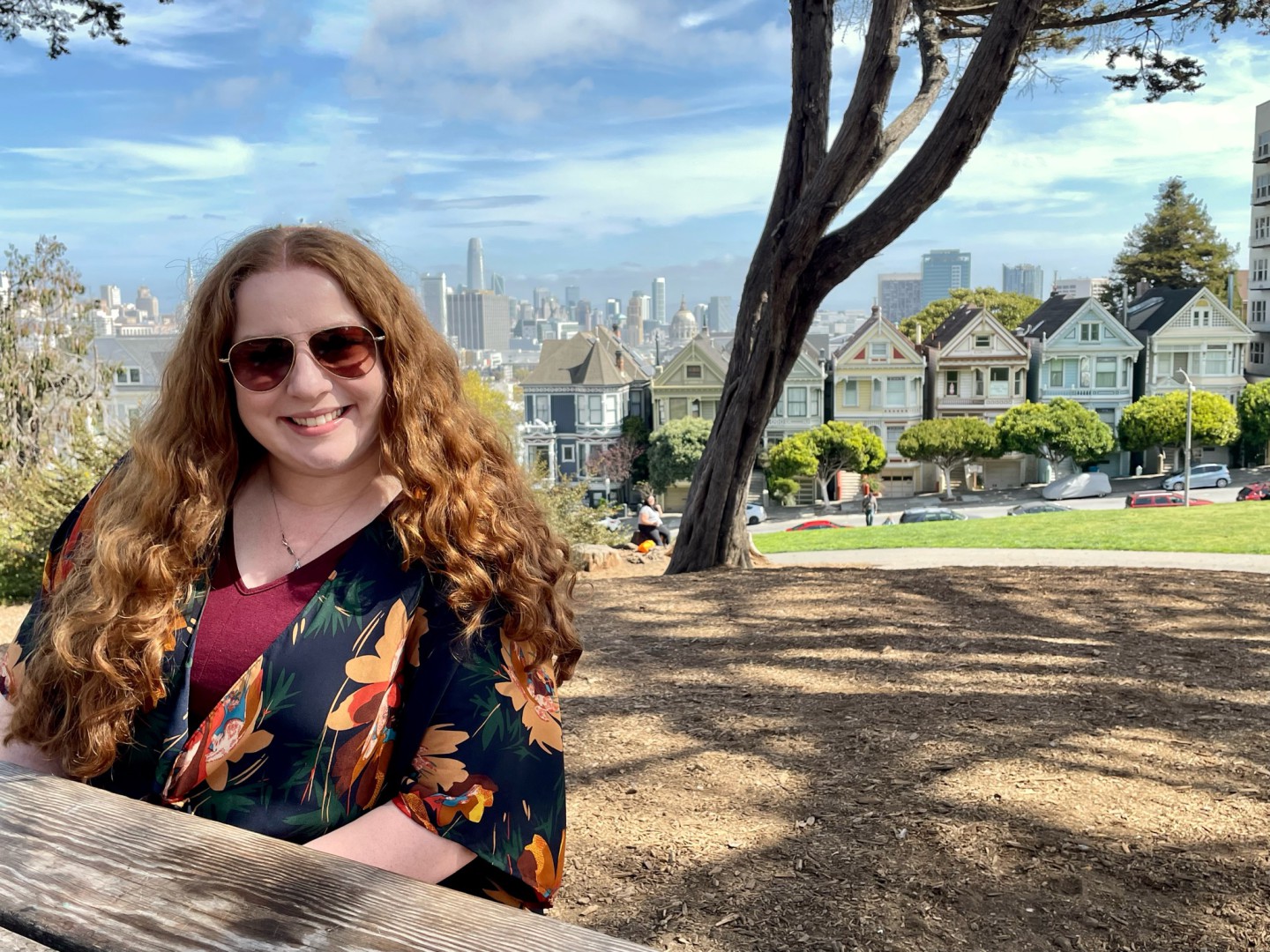 Employee sits on picnic bench in front of city skyline.