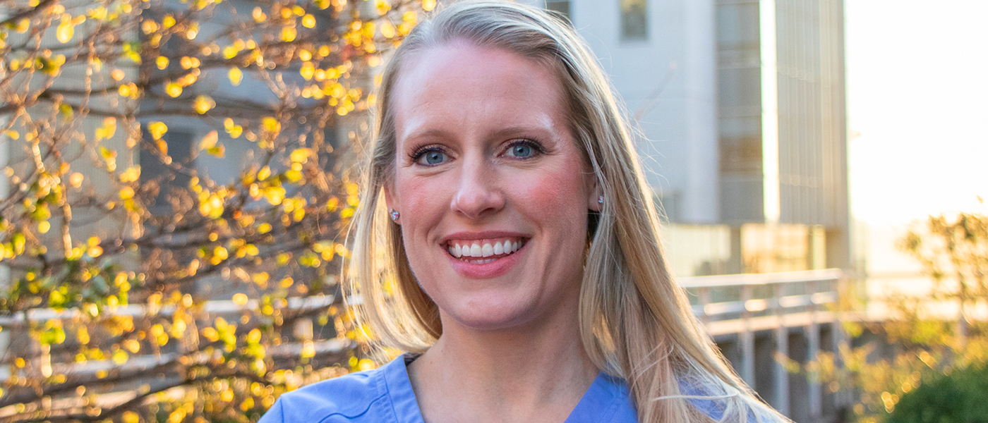 Michelle, a blonde nurse, smiles at the camera outside of a hospital setting.