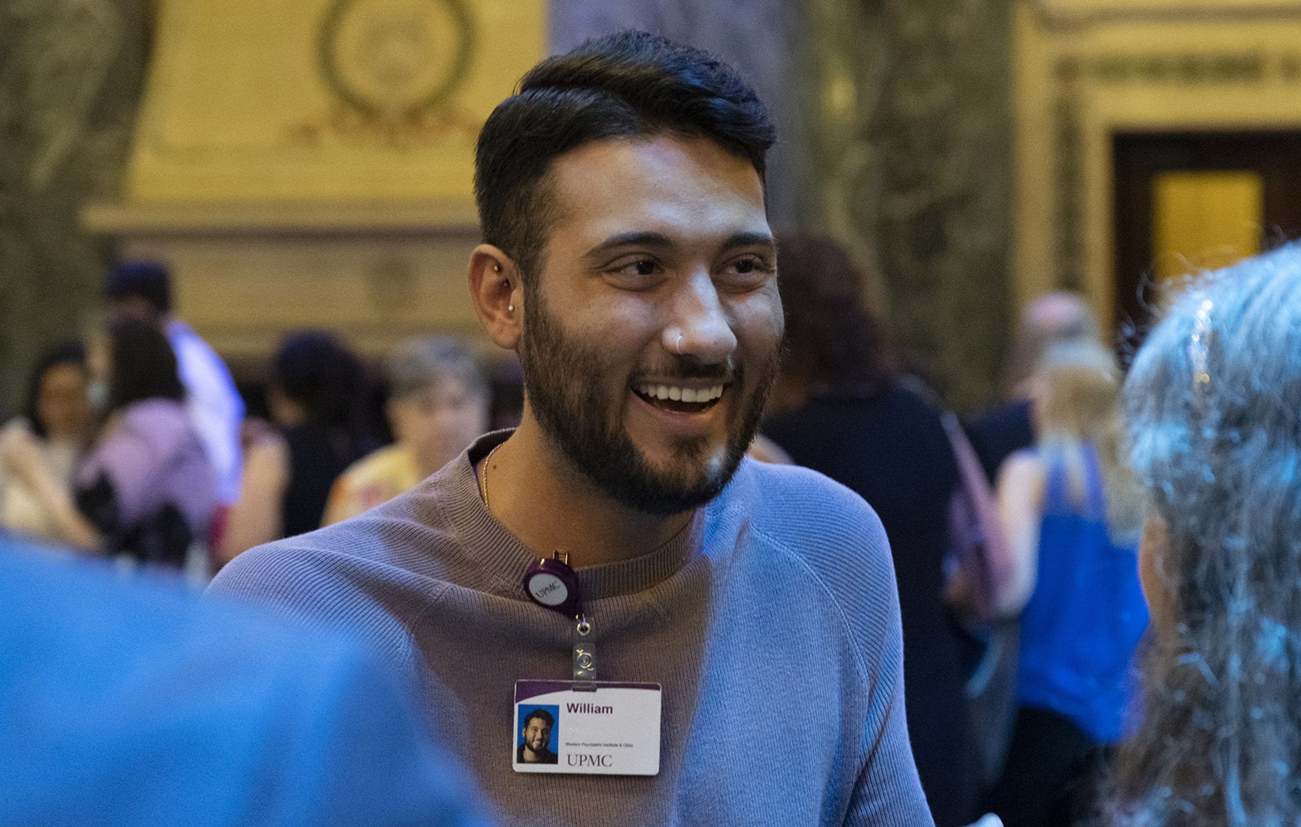 Young man at event talking to others.