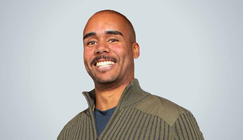 Young man smiles at camera in a studio setting.