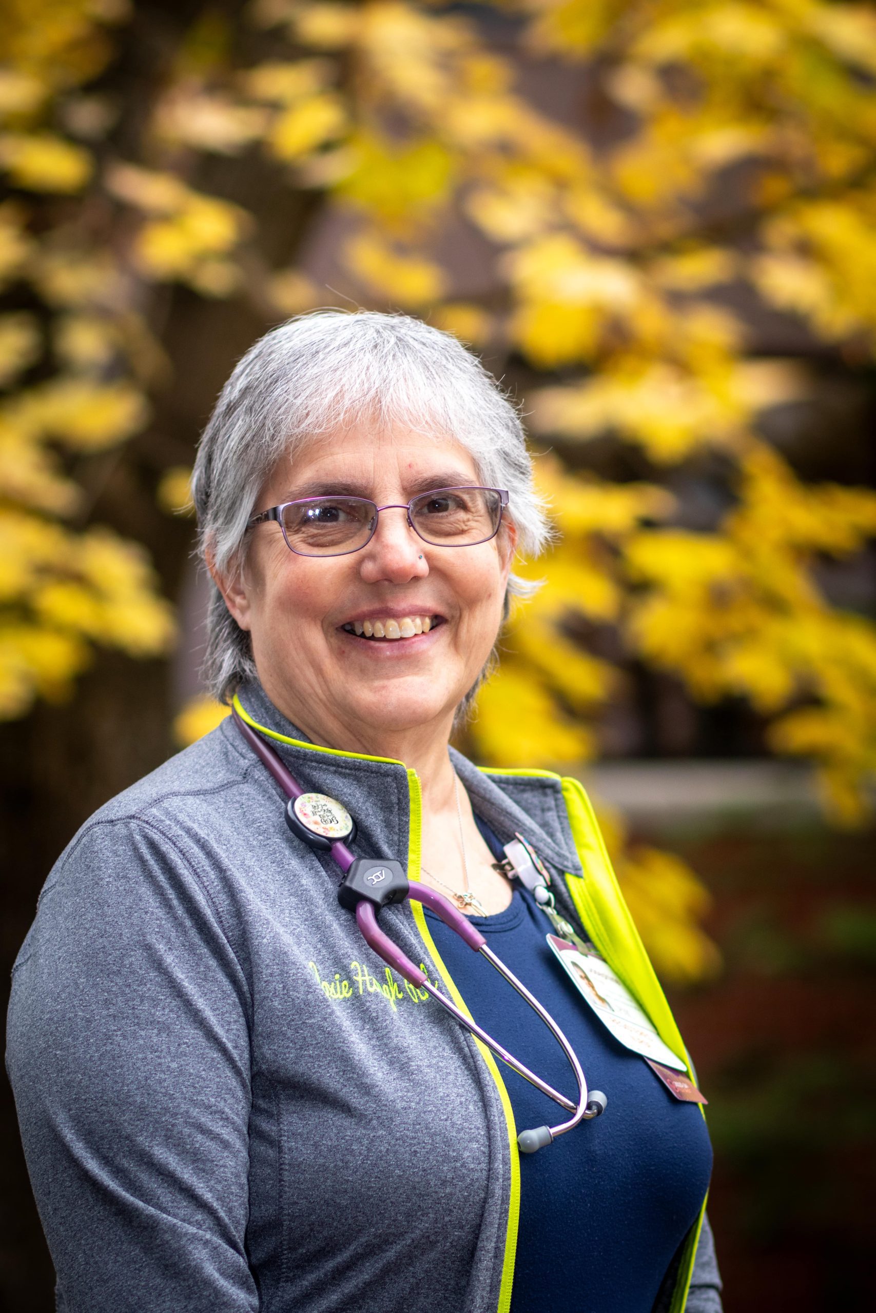 Older female nurse stands outside.