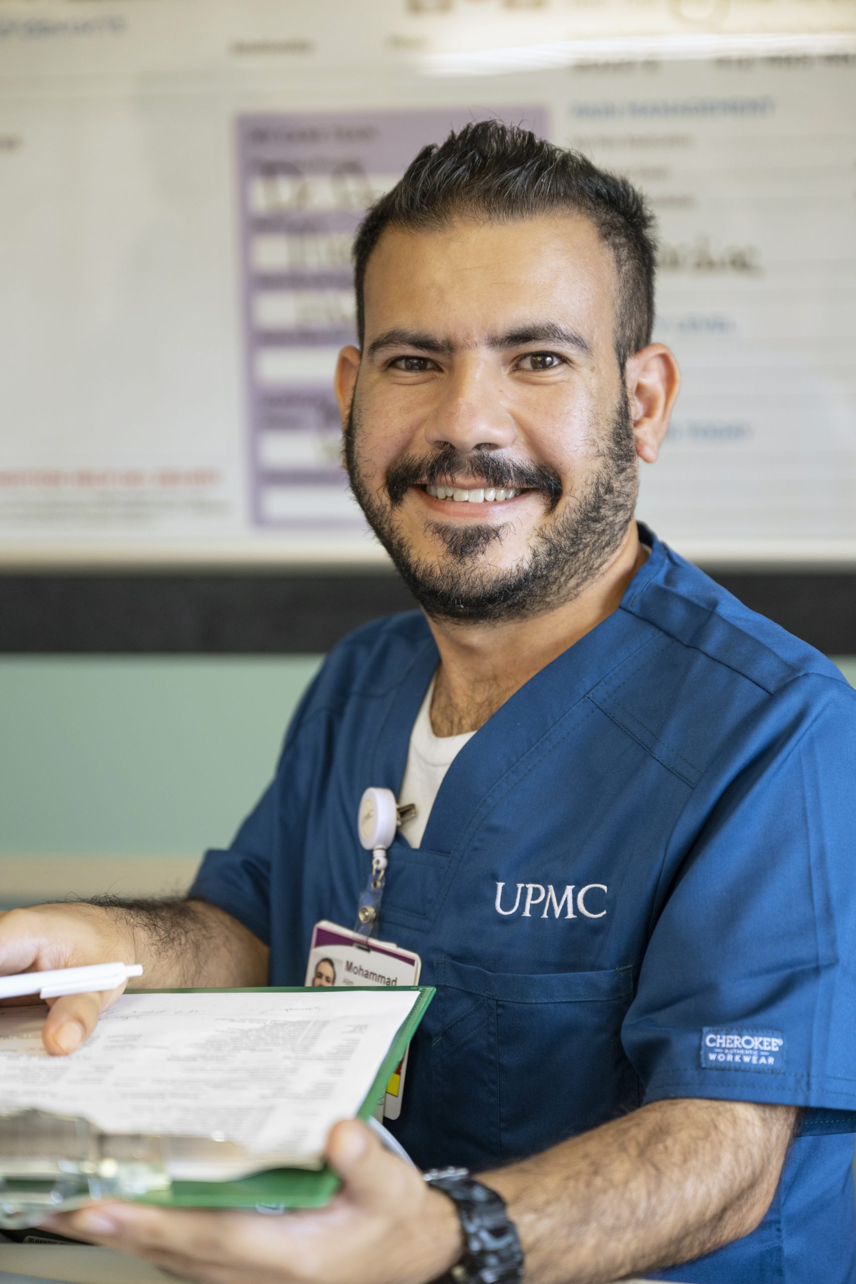 Male nurse with beard in blue scrubs.