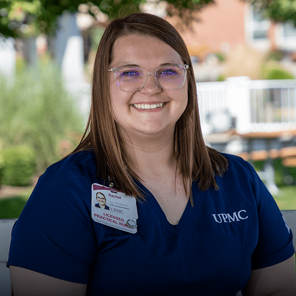 Licensed Practical Nurse in scrubs sits in chair.