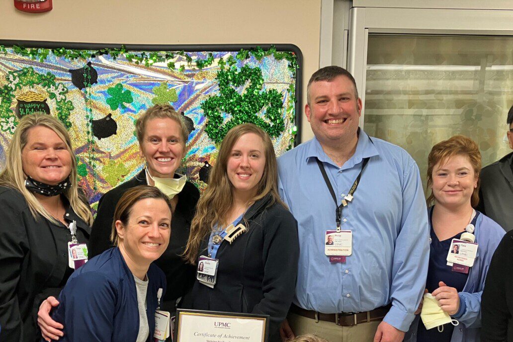 Man with coworkers in the hallway of a hospital.